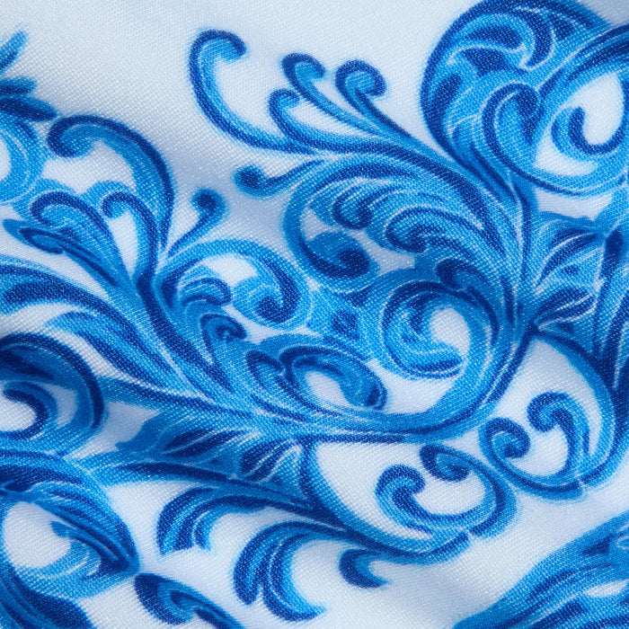 The Gianna Brazilian Bikini Bottom features a blue baroque print swirling with intricate floral, leaf, and vine-like designs over white fabric, creating a decorative and ornate look—perfect for a cheeky or Brazilian-style fit.