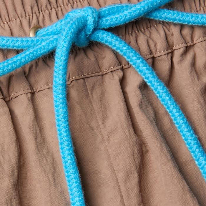 Close-up of the Grayson Nylon Short’s brown crepe nylon waistband, featuring a gathered, elastic texture and finished with a bright blue braided drawstring tied in a bow—a signature detail of this style.