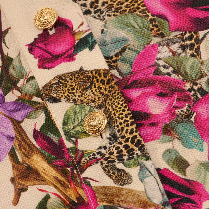 Close-up of the Hestia Cover-Up Romper’s rose leopard print fabric, featuring pink flowers and gold decorative buttons sewn onto the material.