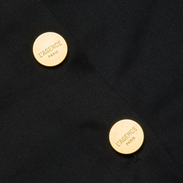 Two round gold buttons engraved with “LAGENCE PARIS” accent the Ida Dress—a tailored style crafted from black fabric—with the buttons positioned diagonally from each other.