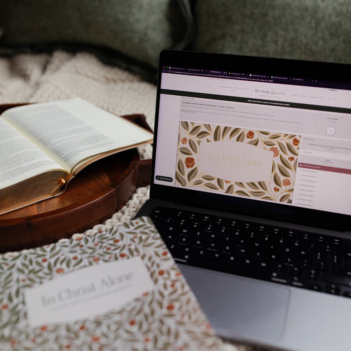 In Christ Alone Study next to an open laptop with the In christ alone study on it with a wooden tray next to the laptop with an open bible on it