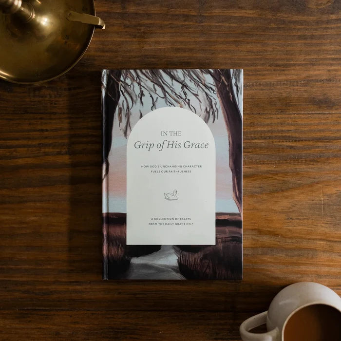 In the Grips of His Grace Study Cover on a brown wooden table next to a bronze oil lamp and a white coffee cup