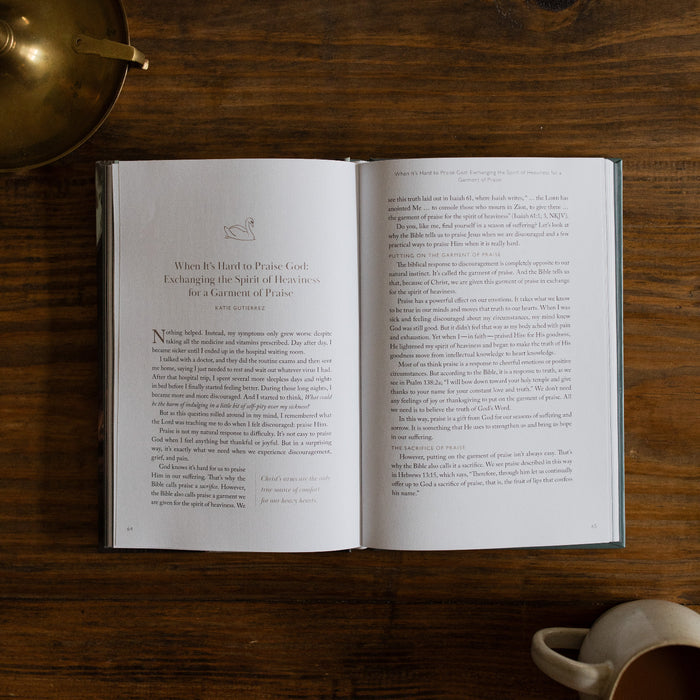 In the Grips of His Grace Study opened to Page 64 about Praising God when its hard, on a brown wooden table next to a bronze oil lamp and a white coffee cup
