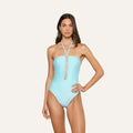 A woman wearing the Indore One-Piece Swimsuit in ice blue, featuring a strapless design with a halter neck and decorative cutout details down the front, stands against a plain light background.