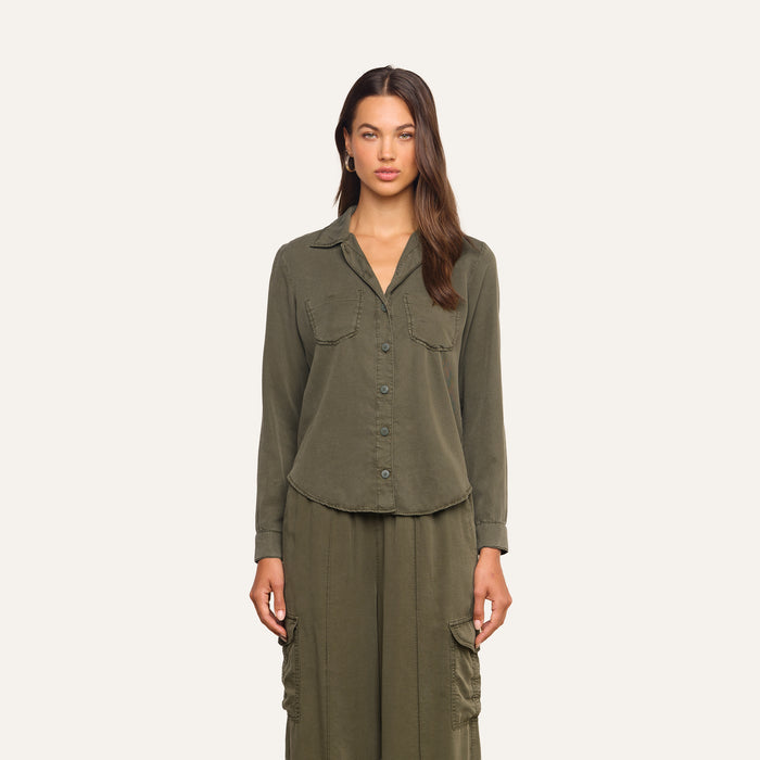 A woman stands facing forward wearing the Isla Shirt in olive green, featuring a collared neckline and two chest pockets, paired with matching cargo-style pants made from featherweight twill, set against a plain light background.