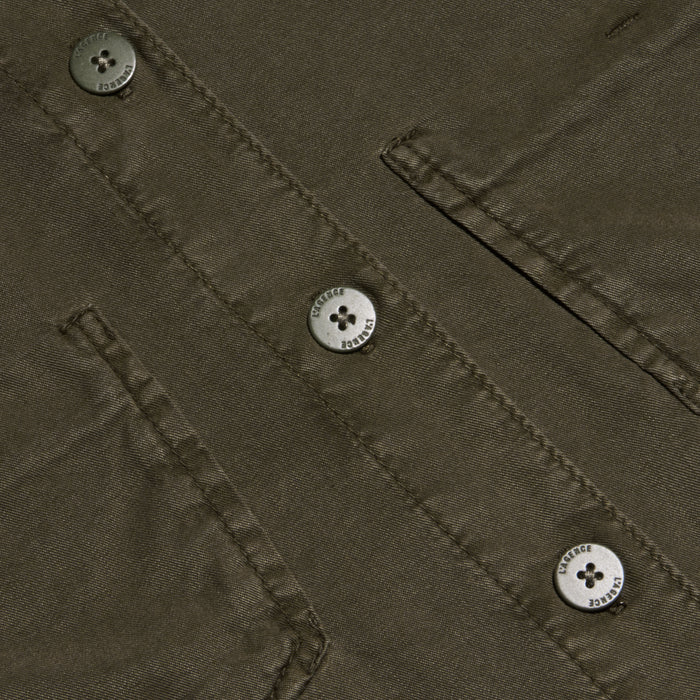 Close-up of the Isla Shirt in olive green featherweight twill, featuring two flap pockets and three four-hole metallic buttons engraved with small text around their edges.