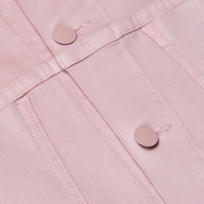 Close-up of the Janelle Coated Jean Jacket in light pink, featuring metal buttons and intersecting stitched seams that highlight the fabric’s textured structure.