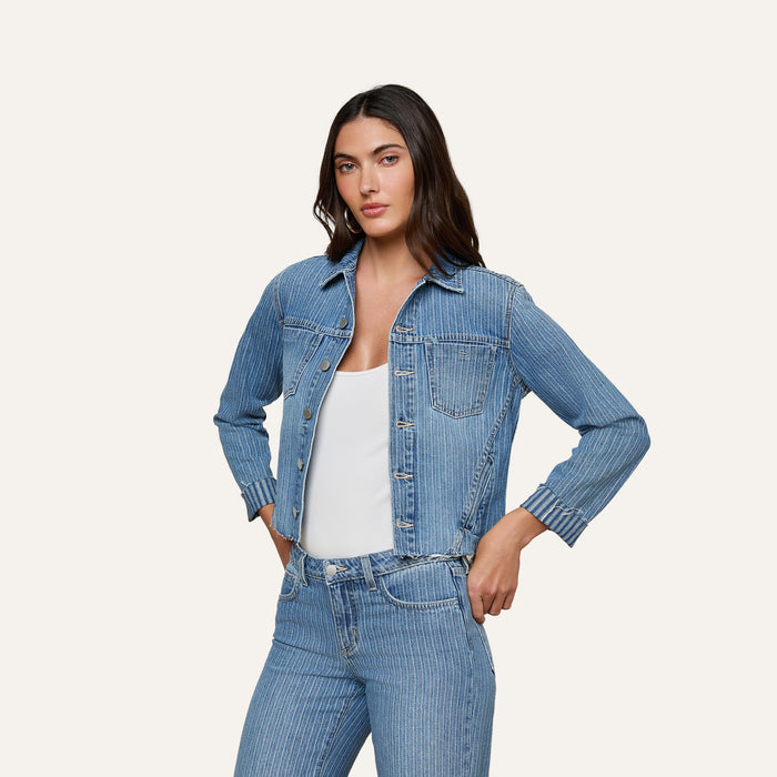 A woman stands with her hands in her pockets, wearing the slim fit Janelle Jean Jacket and matching all-cotton denim jeans over a white top, looking forward against a plain light background.