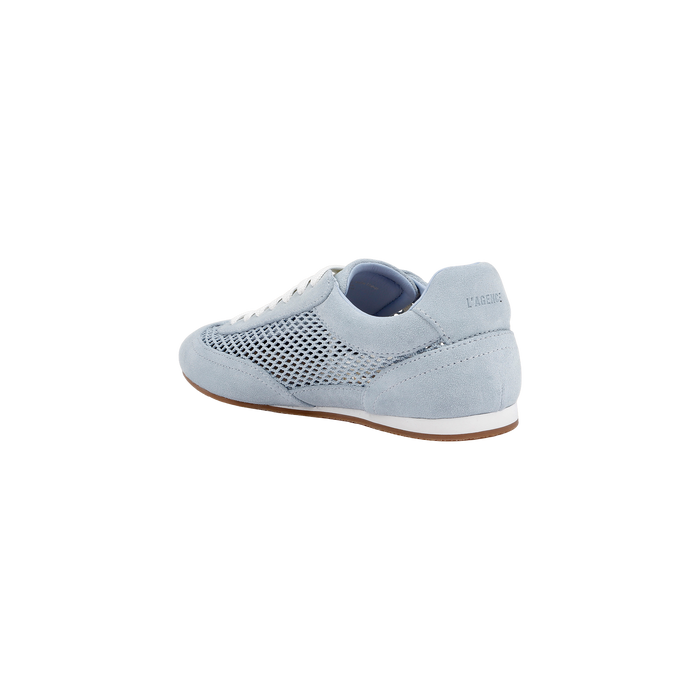 The Jarah Sneaker showcases a retro-inspired design with light blue suede, white laces, a mesh side panel, and a brown sole. Pictured from the back at an angle, the sneaker features the brand name subtly displayed on the heel.