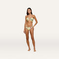 A woman standing and posing in the Jean Bikini Bottom, a yellow butterfly print bikini with a high-leg cut, on a plain light background.
