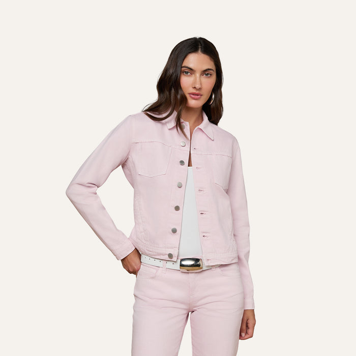 A woman wearing the Celine Jean Jacket in pastel lilac, styled in a slim fit, pairs it with matching pink jeans. She stands with one hand in her pocket and looks confidently at the camera against an off-white, plain background.