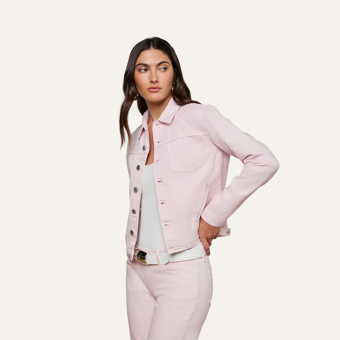 A woman wearing the slim fit Celine Jean Jacket in pastel lilac with matching jeans over a white top, standing against a plain off-white background and looking to the side with one hand on her hip.