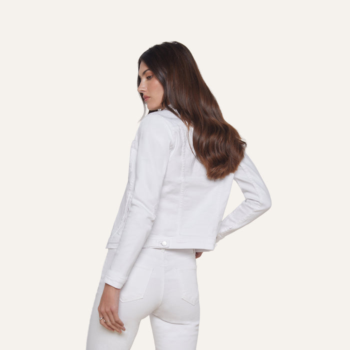 A woman with long brown hair wears the Celine Jean Jacket in optic white, paired with matching white jeans, standing slightly turned to the side against a plain light background.