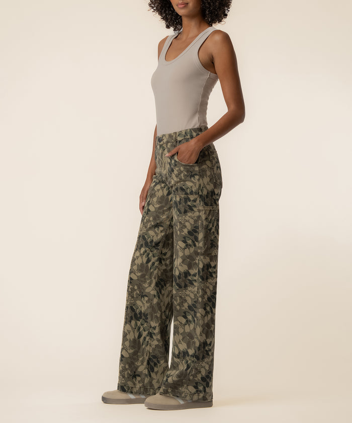 Olive camouflage wide-leg jeans with high rise waistband and front pockets, paired with a cream sleeveless tank top.