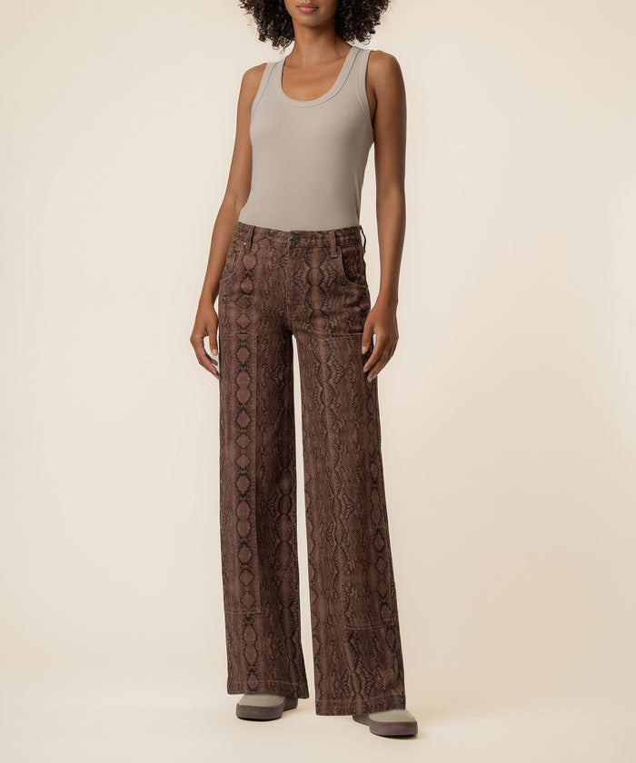 Woman wearing high-rise wide-leg jeans in terrain snake print with a sleeveless gray tank top.