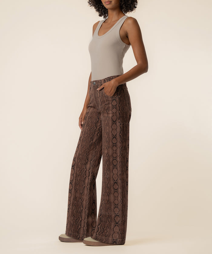 Woman wearing beige sleeveless tank top and brown python-print wide-leg jeans with high waistband.