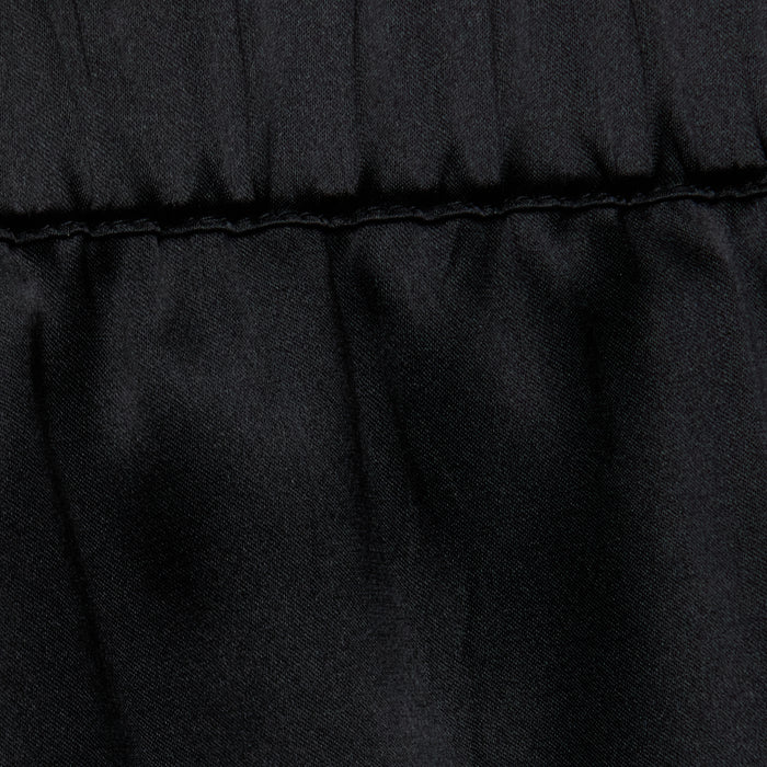 Close-up of the Joy Silk Lace Short in black, featuring a horizontal stitched seam near the top. The fabric above the seam is slightly gathered, forming soft folds and showcasing a smooth, matte texture—perfect for warm-weather style.