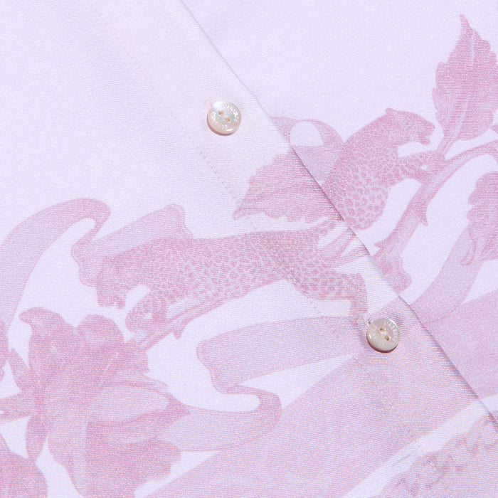 Close-up of the Judy Blouse, a light pink button-down shirt featuring two white buttons and a subtle leopard print and floral pattern in a slightly darker pink shade.