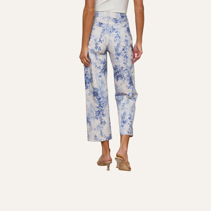 A woman wearing the June Cropped Stovepipe Jean in a white and blue floral paisley print, paired with beige heeled sandals, is shown from the back against a plain light background.