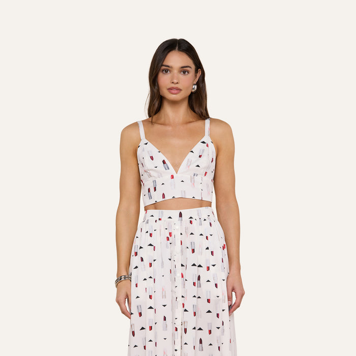 Woman wearing the Kaori Bralette Top, a white sleeveless bralette paired with a matching high-waisted skirt featuring a colorful lipstick print, standing against a plain light background.