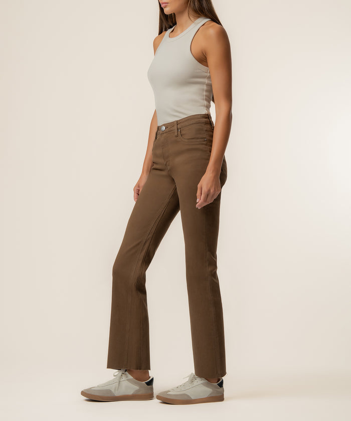Pecan high-rise ankle flare jeans with button closure, paired with white tank top and cream sneakers.