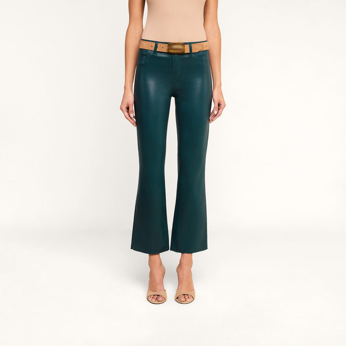 A person wearing a beige top, tan belt, open-toed heels, and the Kendra Coated Cropped Flare Jean in green stands against a plain white background.