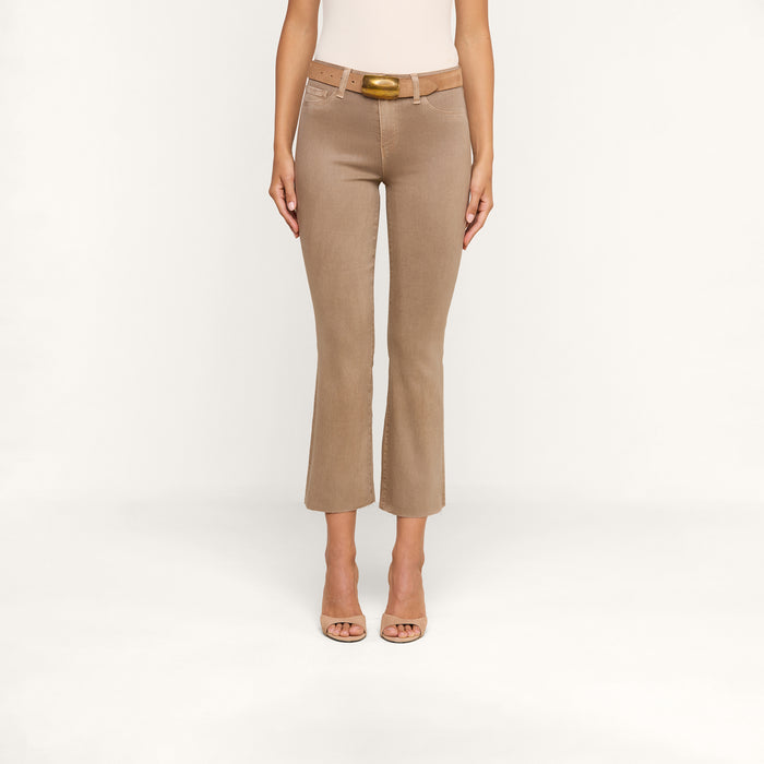 A person wearing the Kendra Coated Cropped Flare Jean in tan, styled with a matching tan belt and open-toe heels, stands against a plain white background with arms relaxed by their sides.