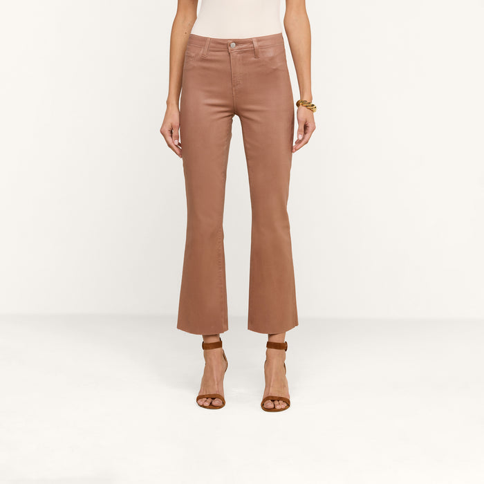 A person wearing Kendra Coated Cropped Flare Jeans in a brown shade and tan high-heeled sandals, standing against a plain white background with their upper body partially visible.