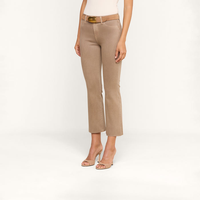 A person wearing the Kendra Coated Cropped Flare Jean in beige, styled with a brown belt and open-toe heels, stands against a plain white background. Only the lower half of their body is visible.