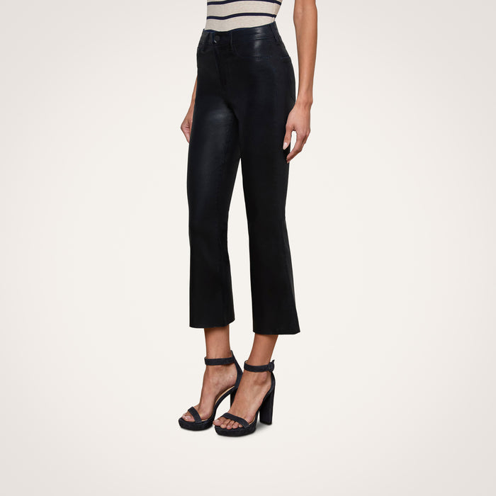 A person wearing Kendra Coated Cropped Flare Jeans in black paired with black high-heeled sandals, standing against a plain light background.