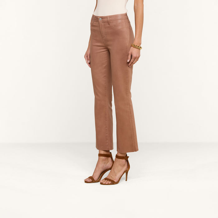 A woman models the Kendra Coated Cropped Flare Jean in high rise brown leather, paired with brown high-heeled sandals. She is standing against a plain white background, with only her lower torso and legs visible.