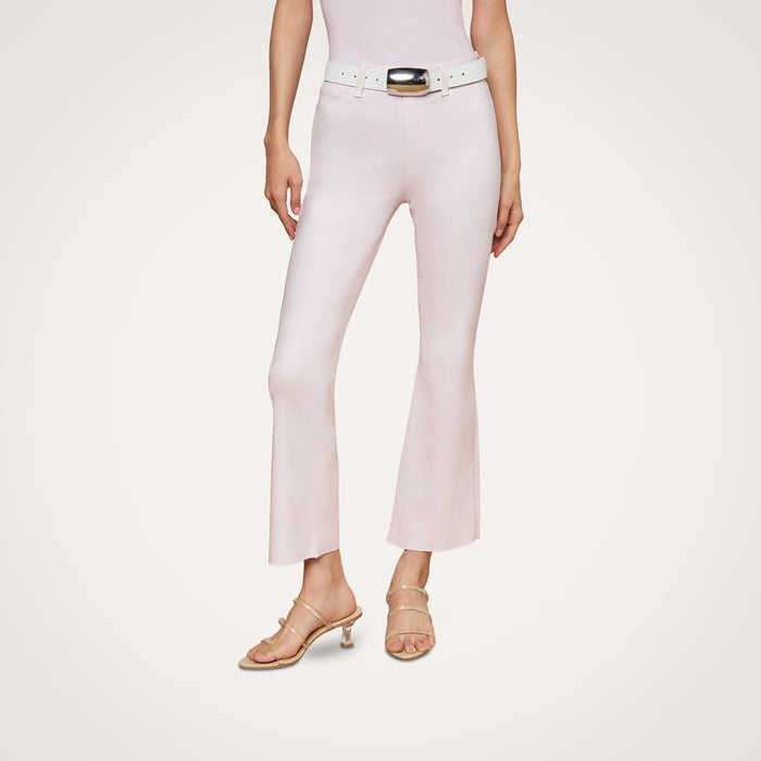 A person is wearing the Kendra Coated Cropped Flare Jean in light pink with a matching belt and beige heeled sandals, standing against a plain white background. Their upper body is partially out of frame.