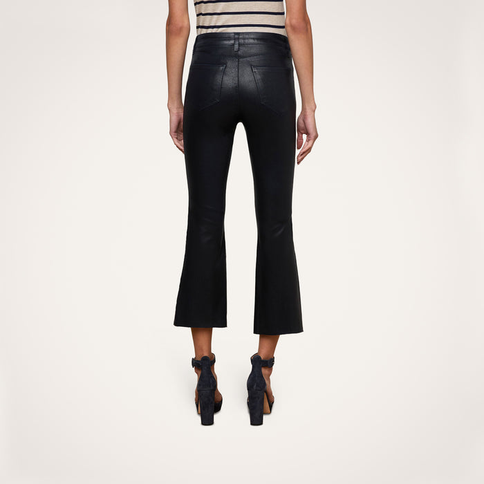 A person wearing the Kendra Coated Cropped Flare Jean in black, paired with a striped sleeveless top and black high-heeled shoes, shown from the back against a plain white background.