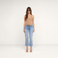 A woman wearing sunglasses, a tan sleeveless top, the Kendra Cropped Flare Jean in light wash, a brown belt, and beige heels stands facing forward against a plain white background.