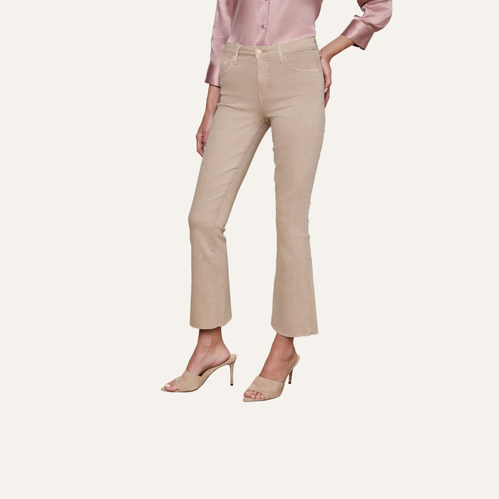 A person wearing the Kendra Cropped Flare Jean, along with a light pink satin blouse and beige high-heeled sandals, stands against a plain light background. Only the lower half of the body is visible.