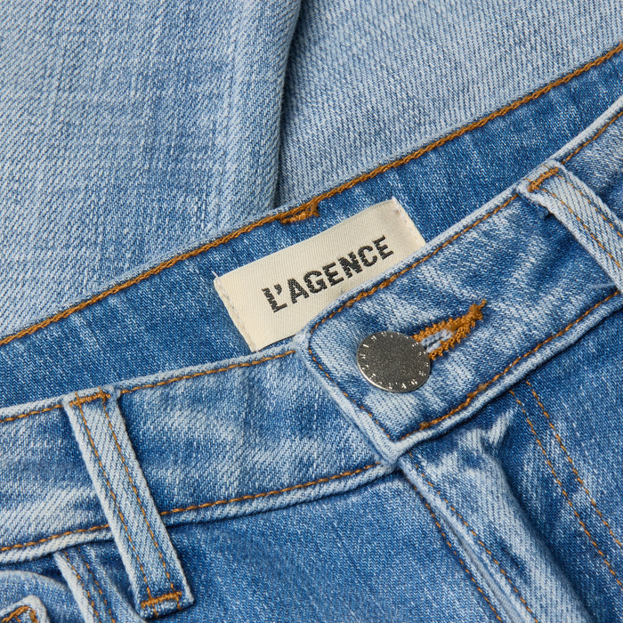 Close-up of light wash denim Kendra Cropped Flare Jean featuring an LAGENCE brand label near the waistband and a metallic button closure, highlighting its stylish cropped flare silhouette.