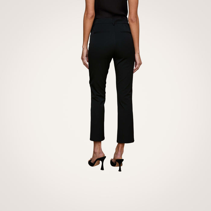 A person is shown from the back wearing the Ketra Bootcut Trouser in black, crafted from midweight suiting fabric, paired with black heels and standing against a plain white background.