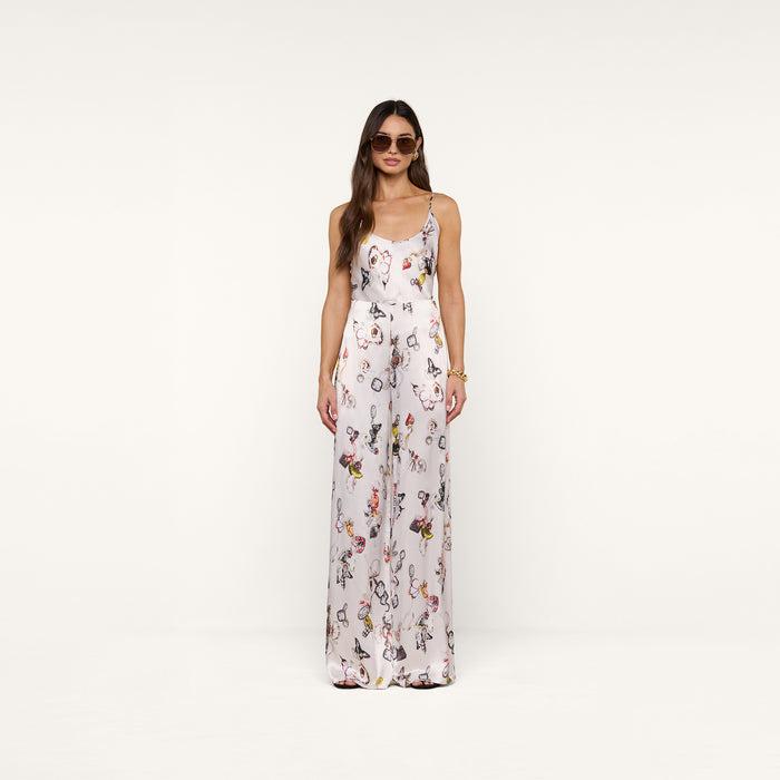 A woman in sunglasses wears the Kimia Satin Pant—a white, high-rise, straight-leg style—paired with a sleeveless floral top, standing against a plain white background and facing forward with her hands by her sides.