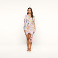A woman stands facing forward, wearing the Kohima Cover-Up Dress—a pastel floral wrap dress with bell sleeves and a tie at the waist—against a plain white background.