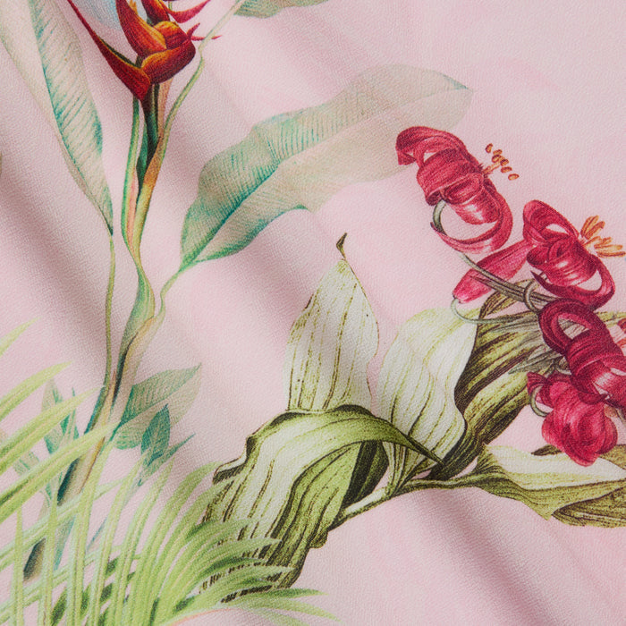 A close-up of the Kohima Cover-Up Dress, showcasing its pink fabric adorned with a colorful botanical print of red flowers, green leaves, and delicate stems—perfect for resort-style poolside wear.