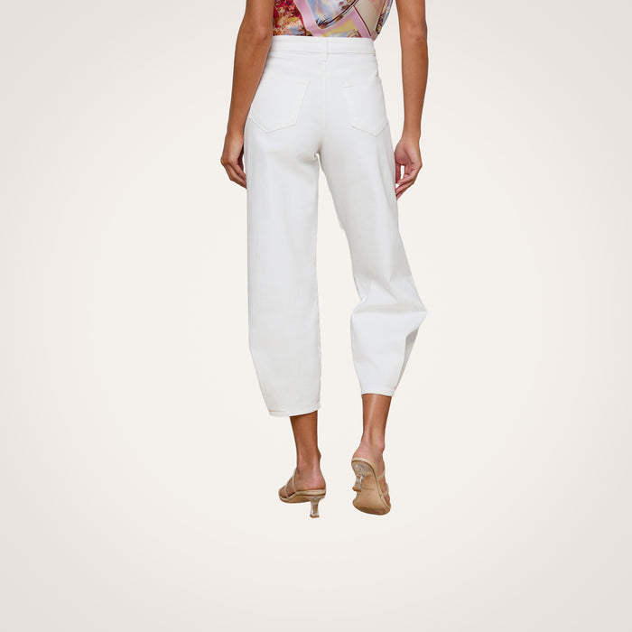 Wearing the Krista Tapered Jean, which features a white high-rise tapered leg in stretch denim, and heeled sandals, a person stands with their back to the camera against a plain light background.
