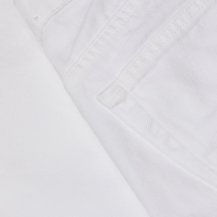 Close-up of the Krista Tapered Jean in white denim, focusing on the pocket and stitched seam details, with textured stretch denim fabric visible. The image highlights the weave and structure characteristic of these high-rise tapered leg jeans.
