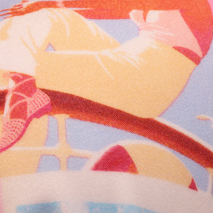 Close-up of a colorful, vintage-style illustration on fabric featuring parts of a figure in light pants and the Kristin Triangle Bikini Top in red, seated with a bicycle wheel appearing at the lower edge of the image.