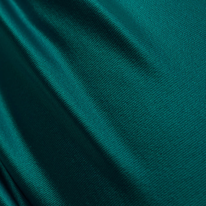 Close-up of smooth, shiny green fabric with subtle folds and a soft texture, reflecting light to create gentle highlights and shadows—reminiscent of the material used in the Krysta Halter Bikini Top.