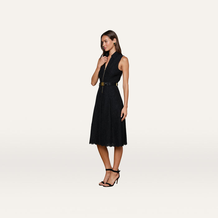 A woman wears the Kylo Lace Shirt Dress, a sleeveless black floral lace design paired with a wide belt and black high-heeled sandals, standing against a plain white background.