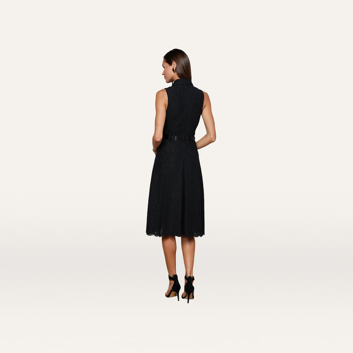 A woman stands facing away, wearing the Kylo Lace Shirt Dress with a belt and black high heels, against a plain light background.