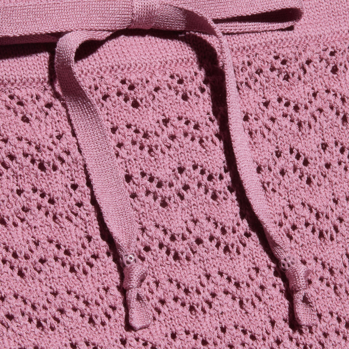 Close-up of the Lacen Pointelle Knit Skirt, featuring a textured, pink breathable pointelle knit fabric with delicate openwork holes and a matching knit drawstring waist tied in a bow at the top.