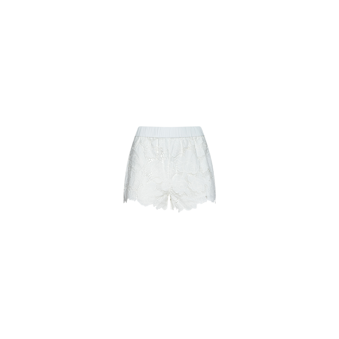 Laina Eyelet Short: Lightweight white shorts with an elastic waistband, featuring a delicate eyelet lace floral pattern and scalloped hem, displayed against a plain white background. Ideal for beachwear.