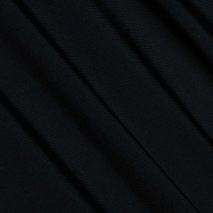 Close-up of the Lambert Paddlesuit’s black four-way stretch nylon fabric, featuring diagonal folds and a fine texture that highlights its detailed weave pattern and the subtle shadows formed by overlapping layers.