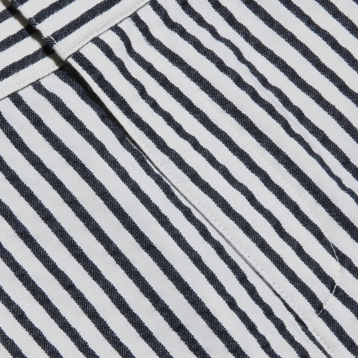 Close-up of the Leni Pedal Pusher’s black and white vertical striped cotton seersucker fabric, showcasing a visible seam and a folded edge that highlight its textured, patterned appearance.